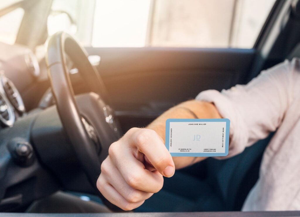 אדם ברכב מושיט רישיון בינלאומי או תעודת זהות מבעד לחלון הפתוח, ומתמקד בכרטיס.